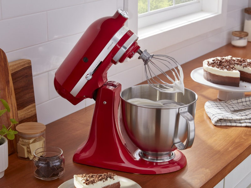 Red KitchenAid® stand mixer whipping cream next to pie on counter