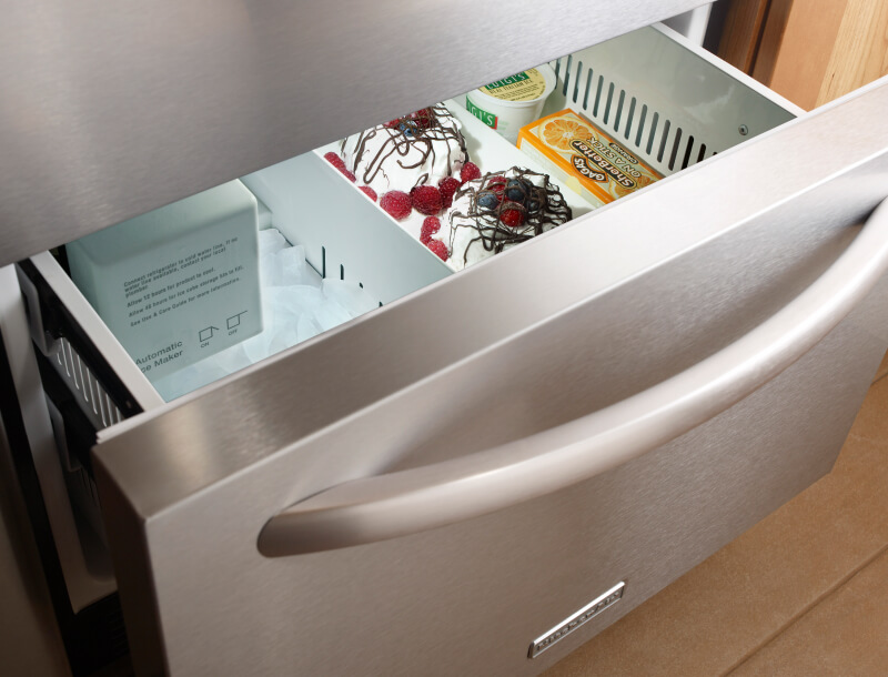 Freezer drawer slightly ajar with ice cream and sorbet inside