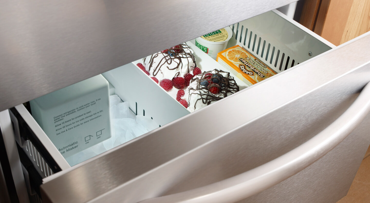 Freezer drawer slightly ajar with ice cream and sorbet inside