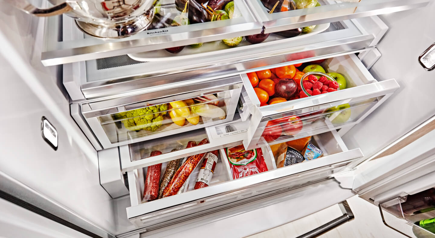 Stocked refrigerator with fruits and vegetables stored in crisper drawers