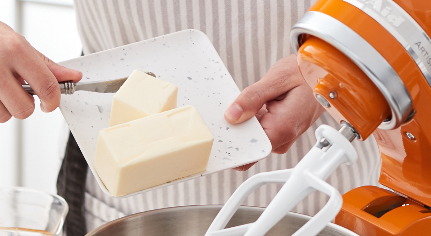 Person adding butter to a KitchenAid® stand mixer bowl
