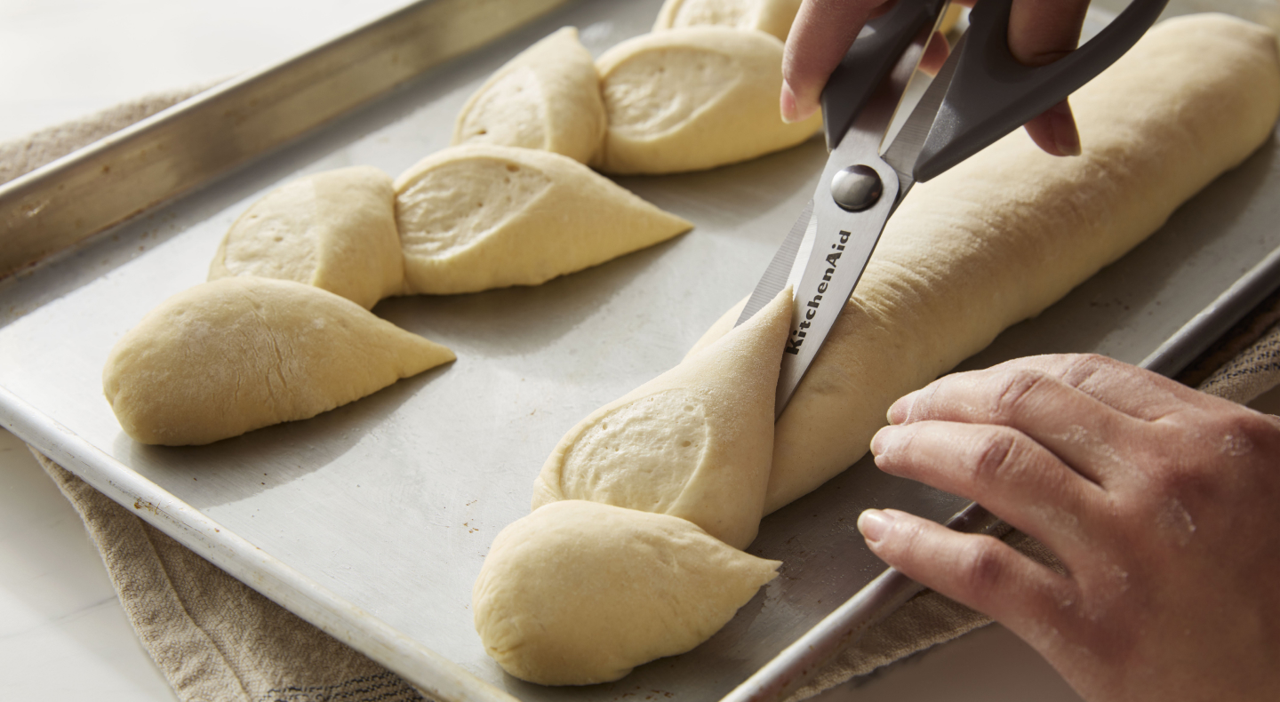 A person scoring bread with scissors