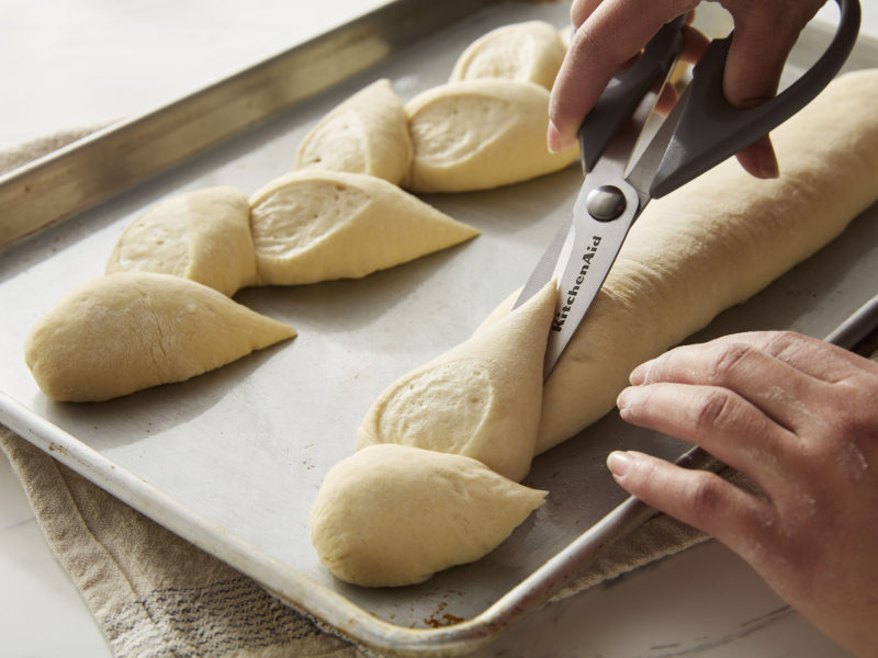 A person scoring bread with scissors