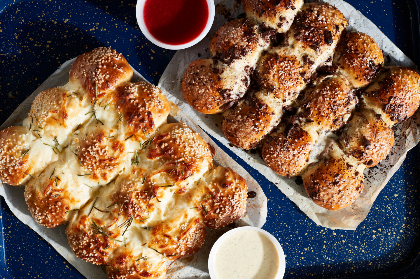Savory pretzel rolls on parchment paper next to various dips