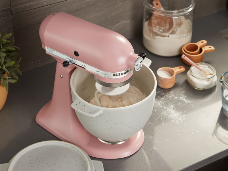 Pink stand mixer with white speckled stand mixer bowl full of flour