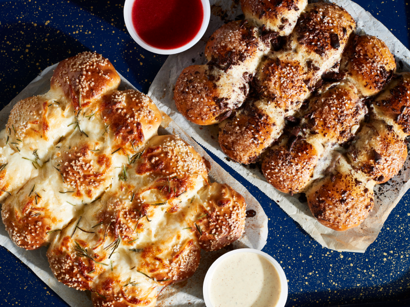 Savory pretzel rolls on parchment paper next to various dips