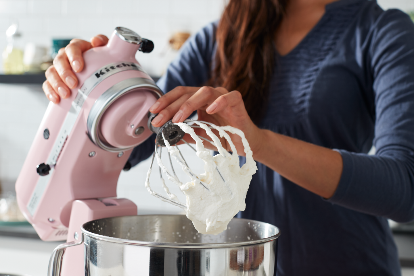 A woman using a pink KitchenAid® stand mixer to make homemade whipped cream