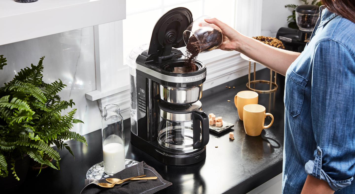 Person putting coffee grounds in a coffee maker