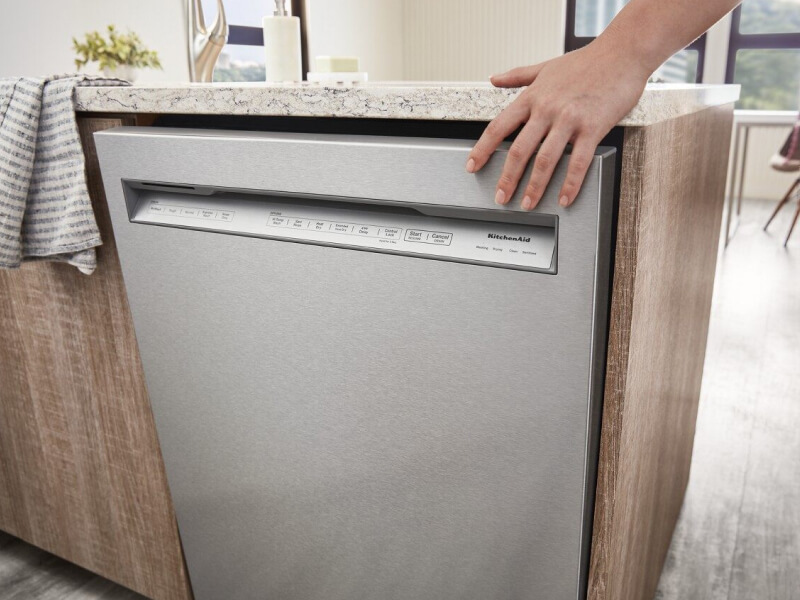 Hand touching a KitchenAid® front control dishwasher