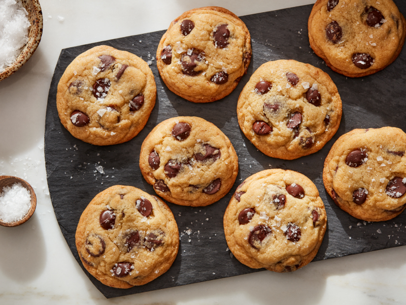 Sea salt miso chocolate chunk cookies on a board next to bowl of sea salt