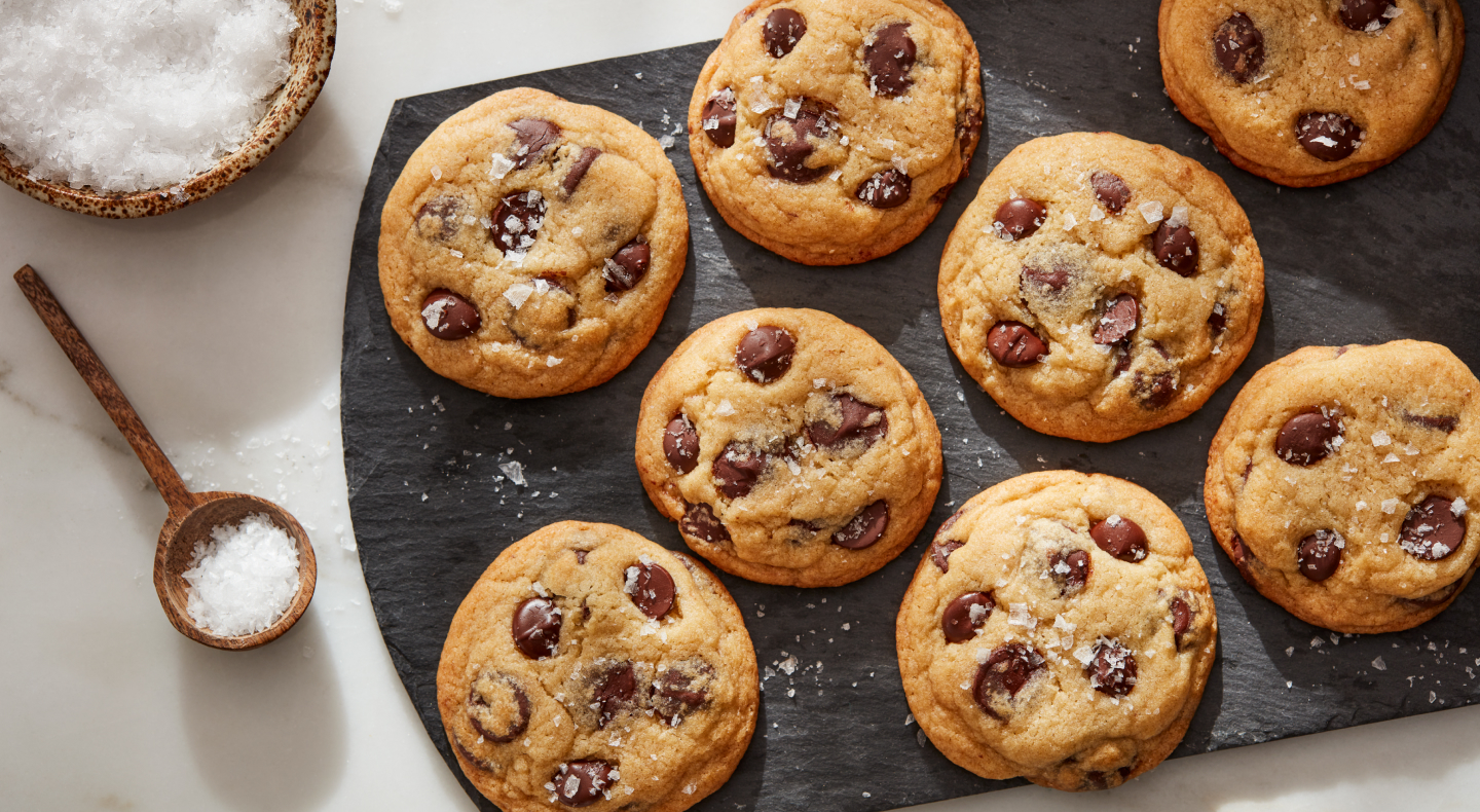 Sea salt miso chocolate chunk cookies on a board next to bowl of sea salt