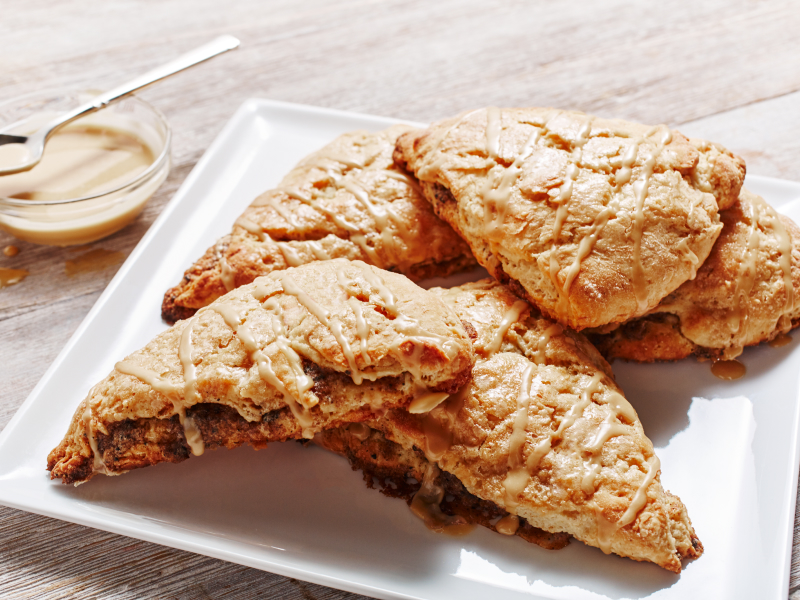 Cinnamon coffee scones on a plate next to honey butter serving dish