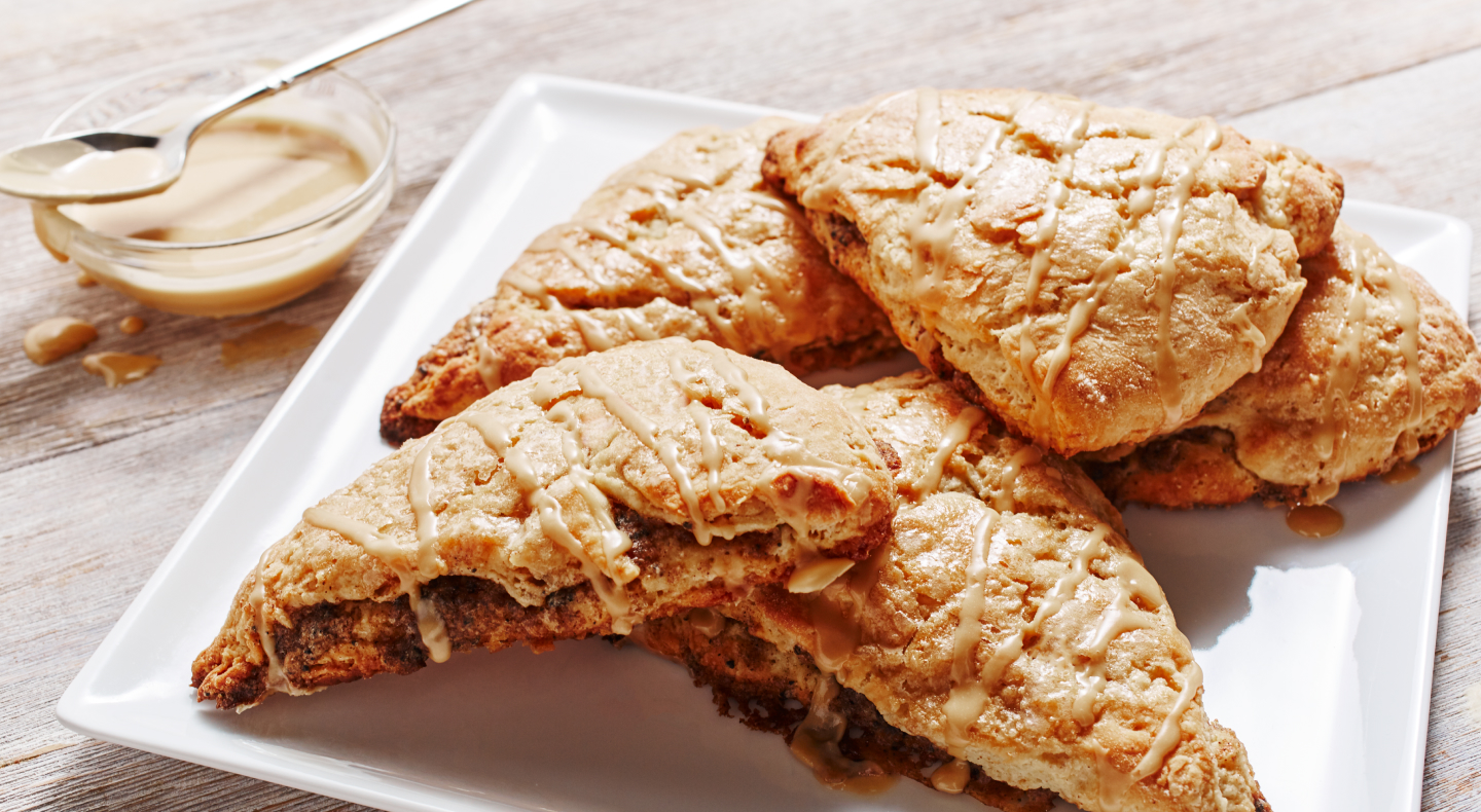 Cinnamon coffee scones on a plate next to honey butter serving dish