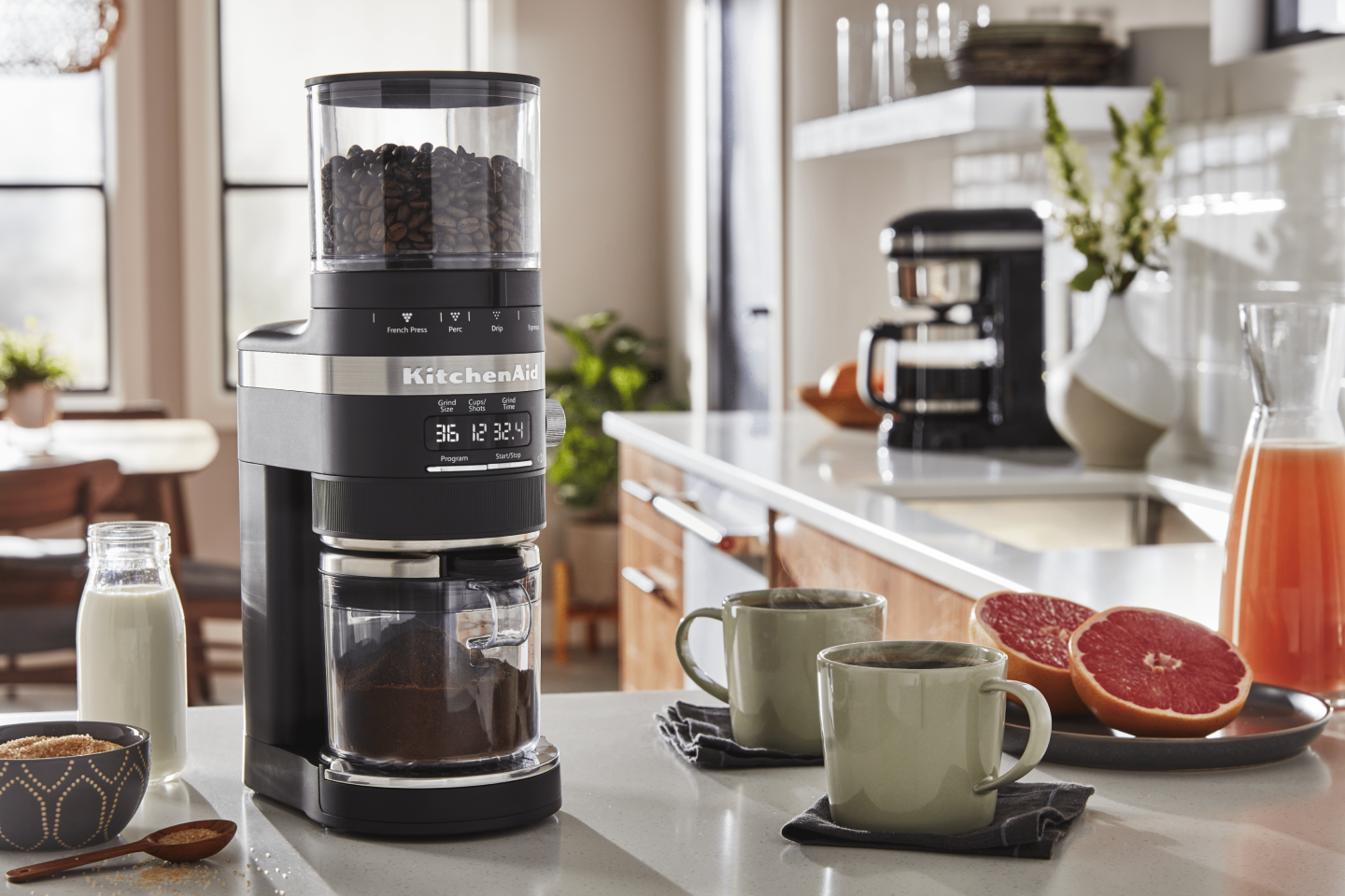 Coffee beans in a black KitchenAid® Burr Coffee Grinder in a modern kitchen