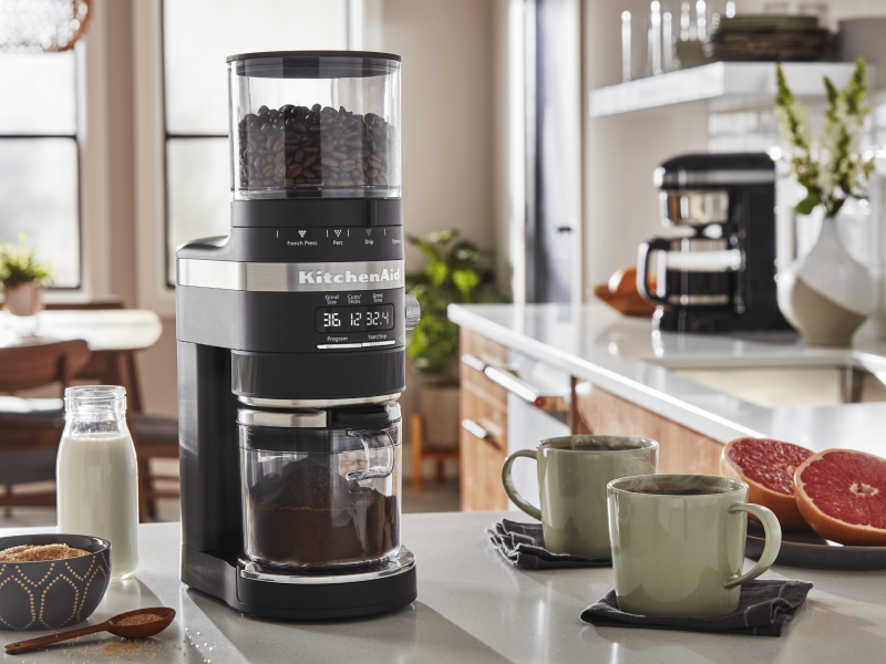 Coffee beans in a black KitchenAid® Burr Coffee Grinder in a modern kitchen