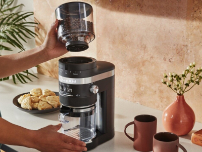 Coffee beans being placed on the base of burr coffee grinder.