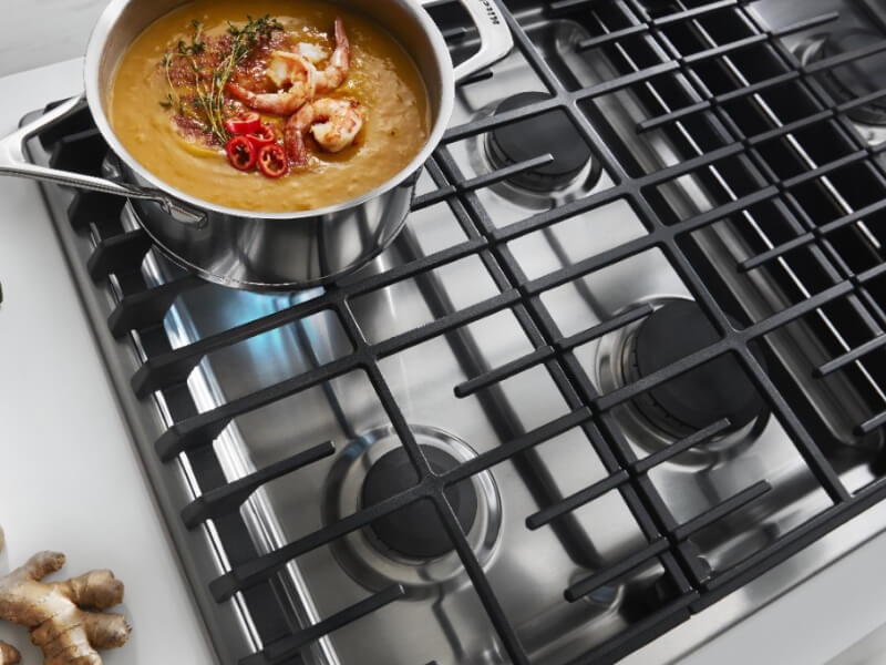 An overhead view of a KitchenAid® gas cooktop simmering a pot of food