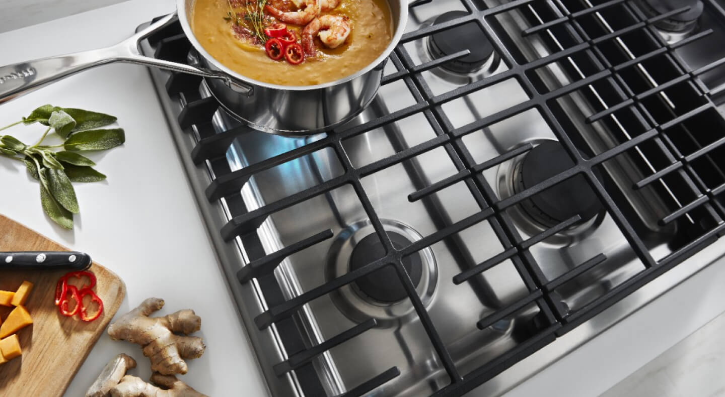 An overhead view of a KitchenAid® gas cooktop simmering a pot of food
