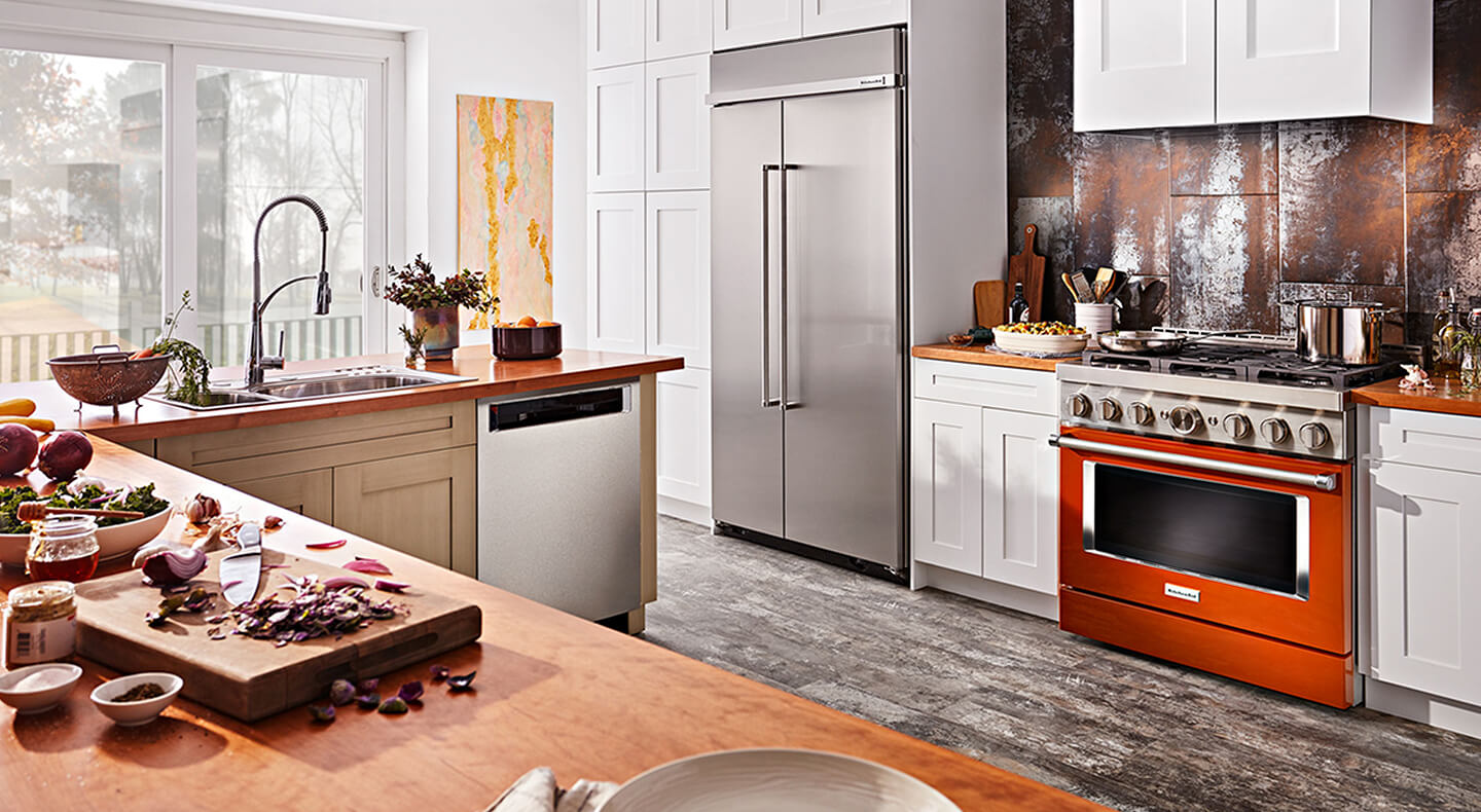 A bright, G-shaped kitchen with a scorched orange KitchenAid® commercial-style gas range