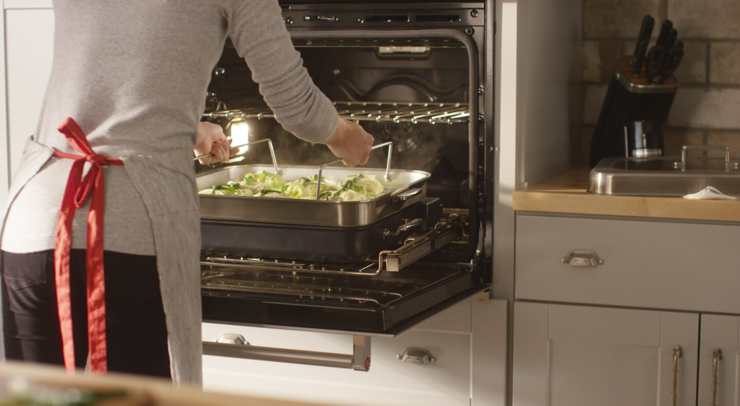 Person placing a baking dish of food in an oven