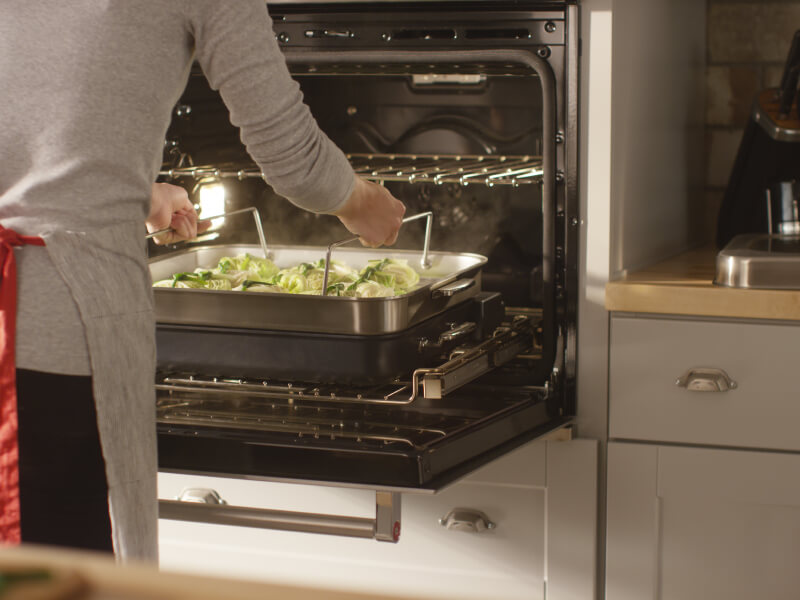 Person placing a baking dish of food in an oven