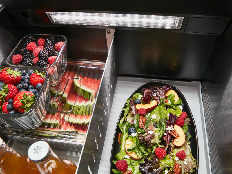 Fresh fruit and a salad stored inside a refrigerator