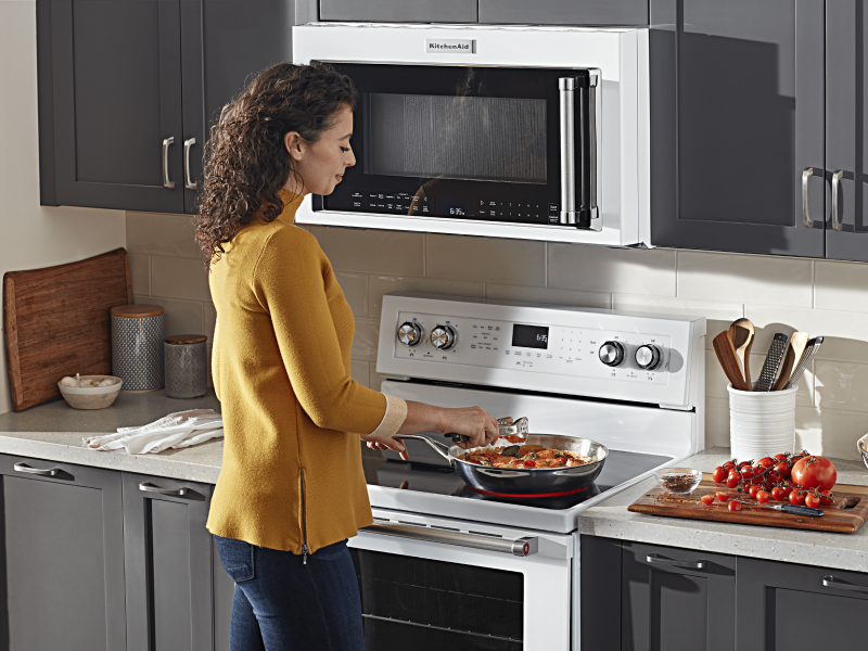 Person adding ingredients to a skillet on an electric stovetop 