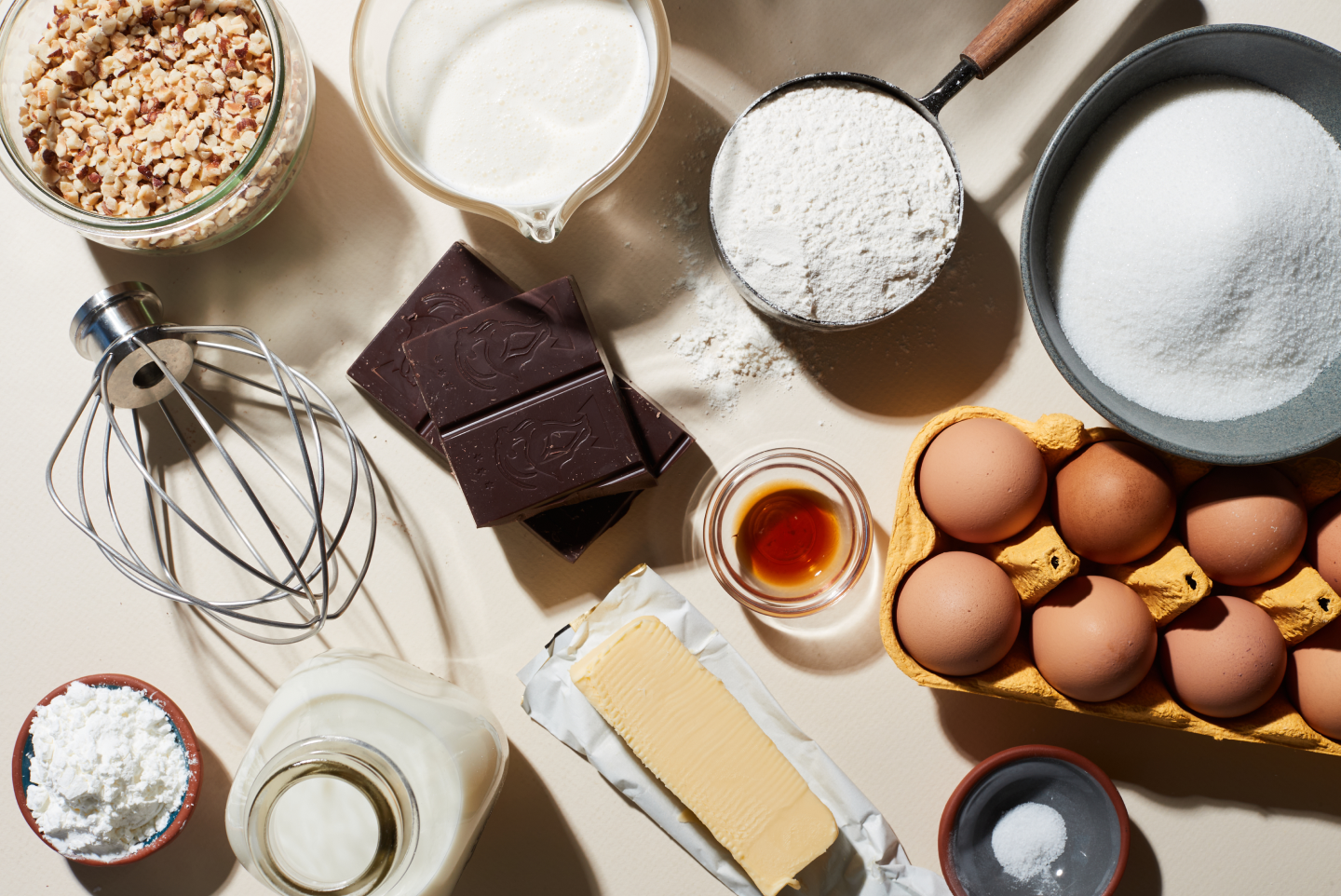 Top view of whisk attachment and pie ingredients including flour, sugar, eggs, butter, milk, chocolate and walnuts