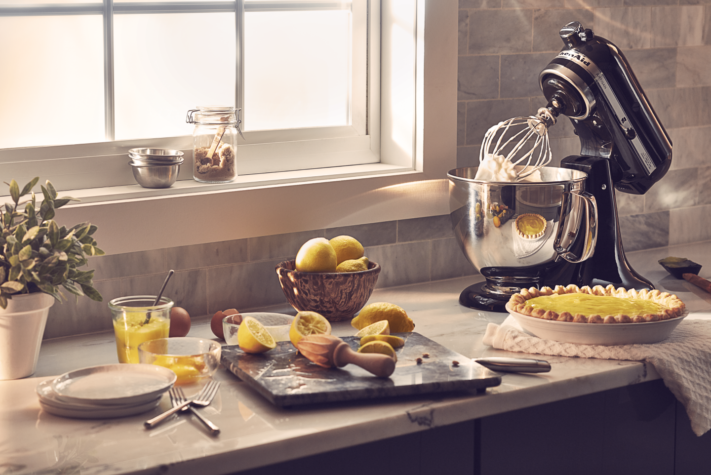 Black KitchenAid® stand mixer on countertop next to lemon custard pie with other baking ingredients
