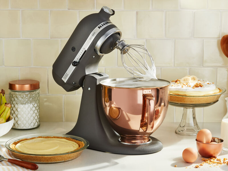 A KitchenAid® stand mixer with a wire whisk/whip accessory with fresh whipped egg whites on the counter of a modern kitchen.