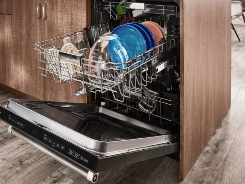 Opened dishwasher with top rack full of colored plates