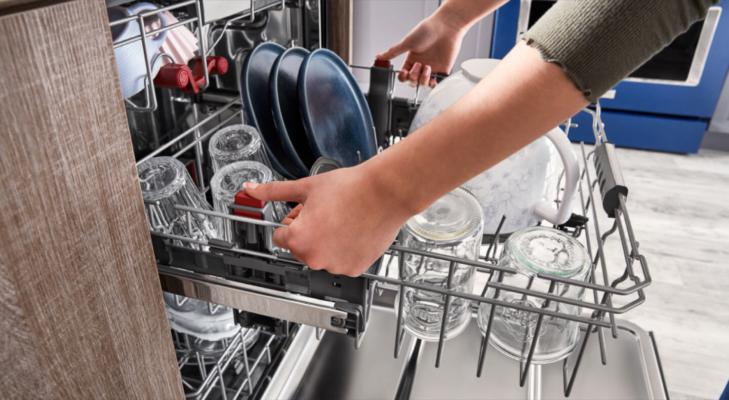 Dishwasher rack filled with clear glasses and blue plates