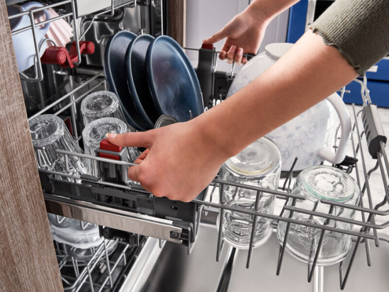 Dishwasher rack filled with clear glasses and blue plates