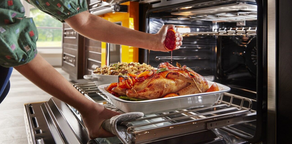 Woman squeezing an orange over a roasting chicken