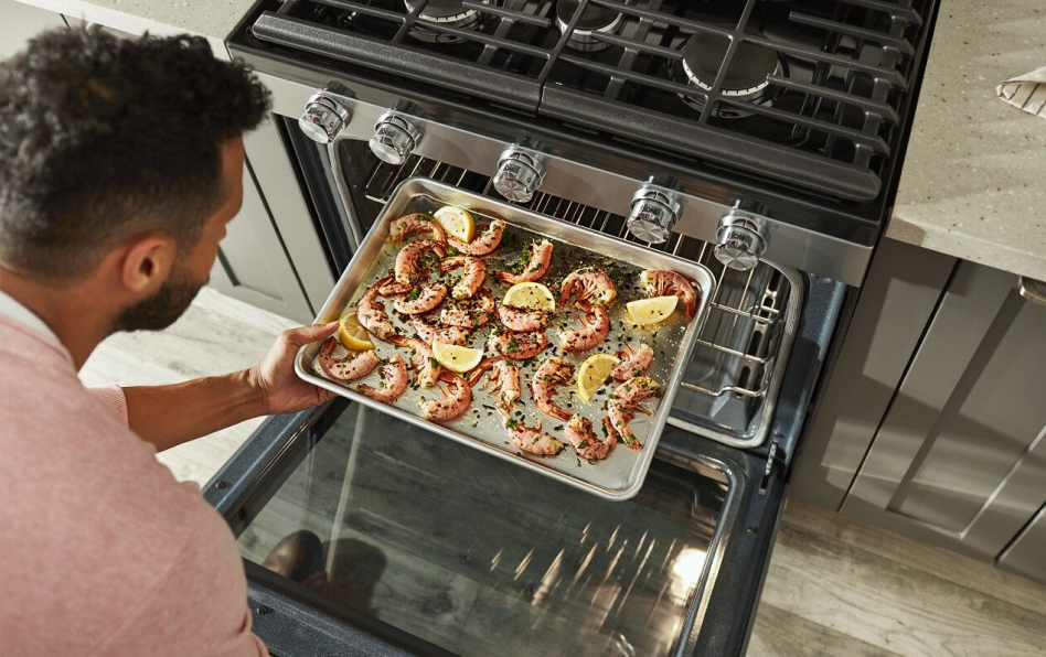 Man pulling pan with shrimp out of convection oven
