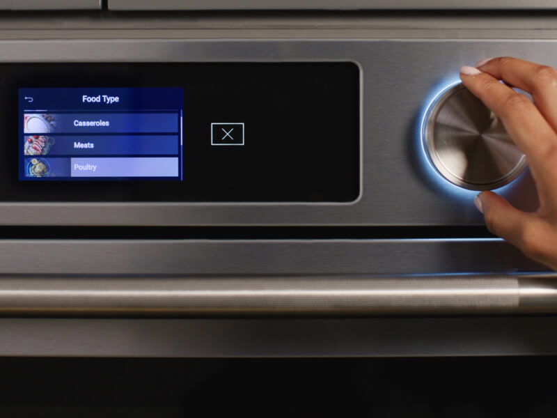 Person selecting settings on a wall oven touch screen
