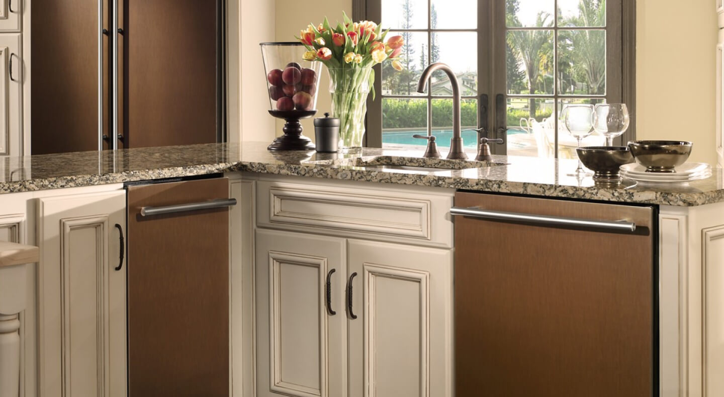 The inside of a traditional looking kitchen with marble countertops and a trash compactor