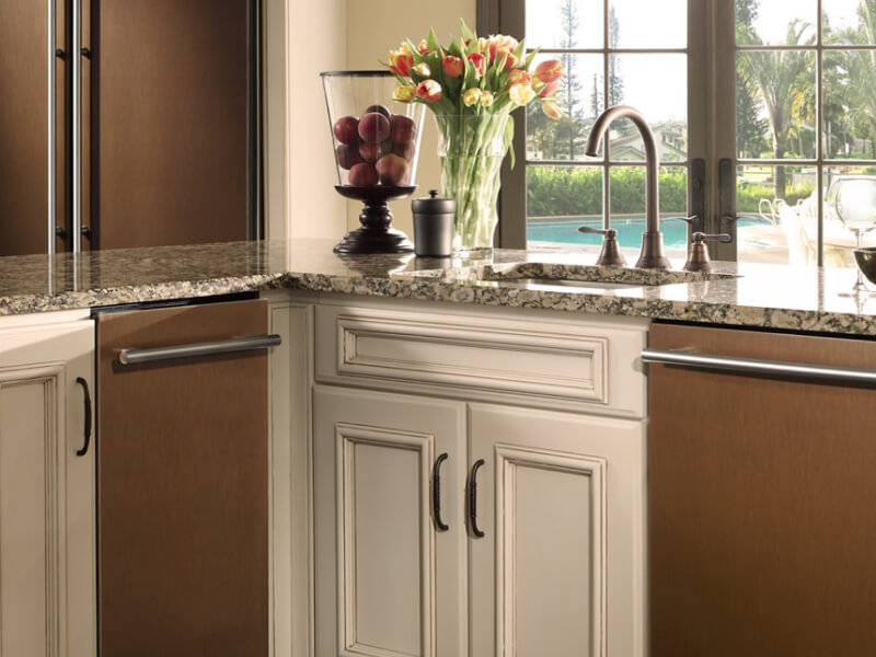 The inside of a traditional looking kitchen with marble countertops and a trash compactor