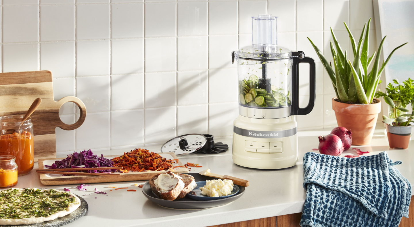 KitchenAid® food processor with grated zucchini and homemade pizza ingredients