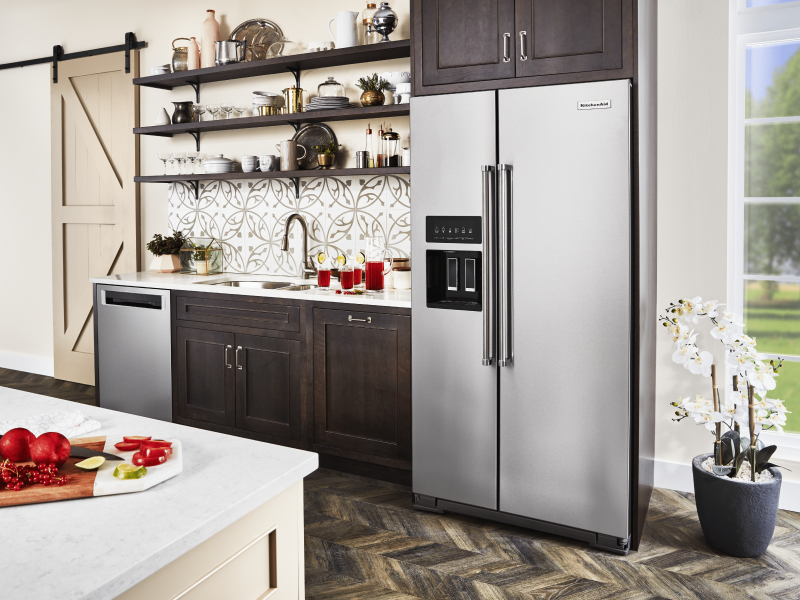 Stainless steel KitchenAid® side-by-side refrigerator next to kitchen sink countertop