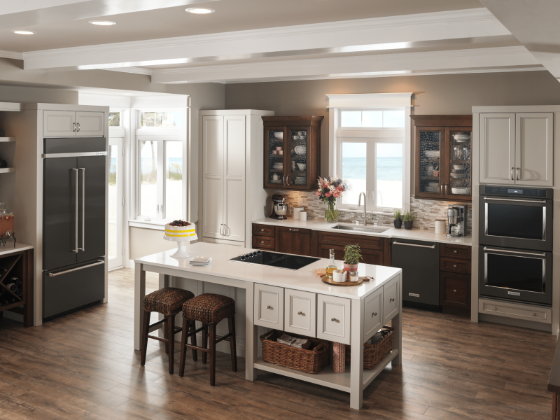 Full kitchen view with black french door refrigerator adjacent to island cooktop