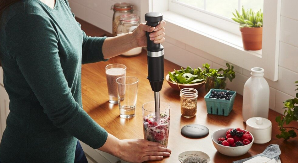 Woman blending smoothie with black KitchenAid® cordless immersion blender