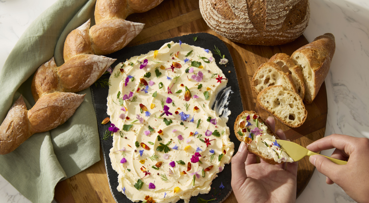 Person spreading dip on toasted a baguette