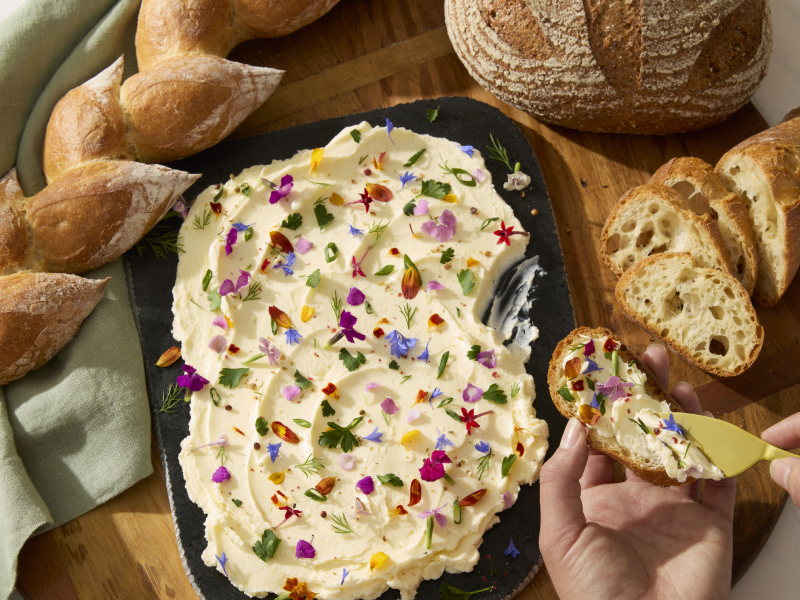 Person spreading dip on toasted a baguette