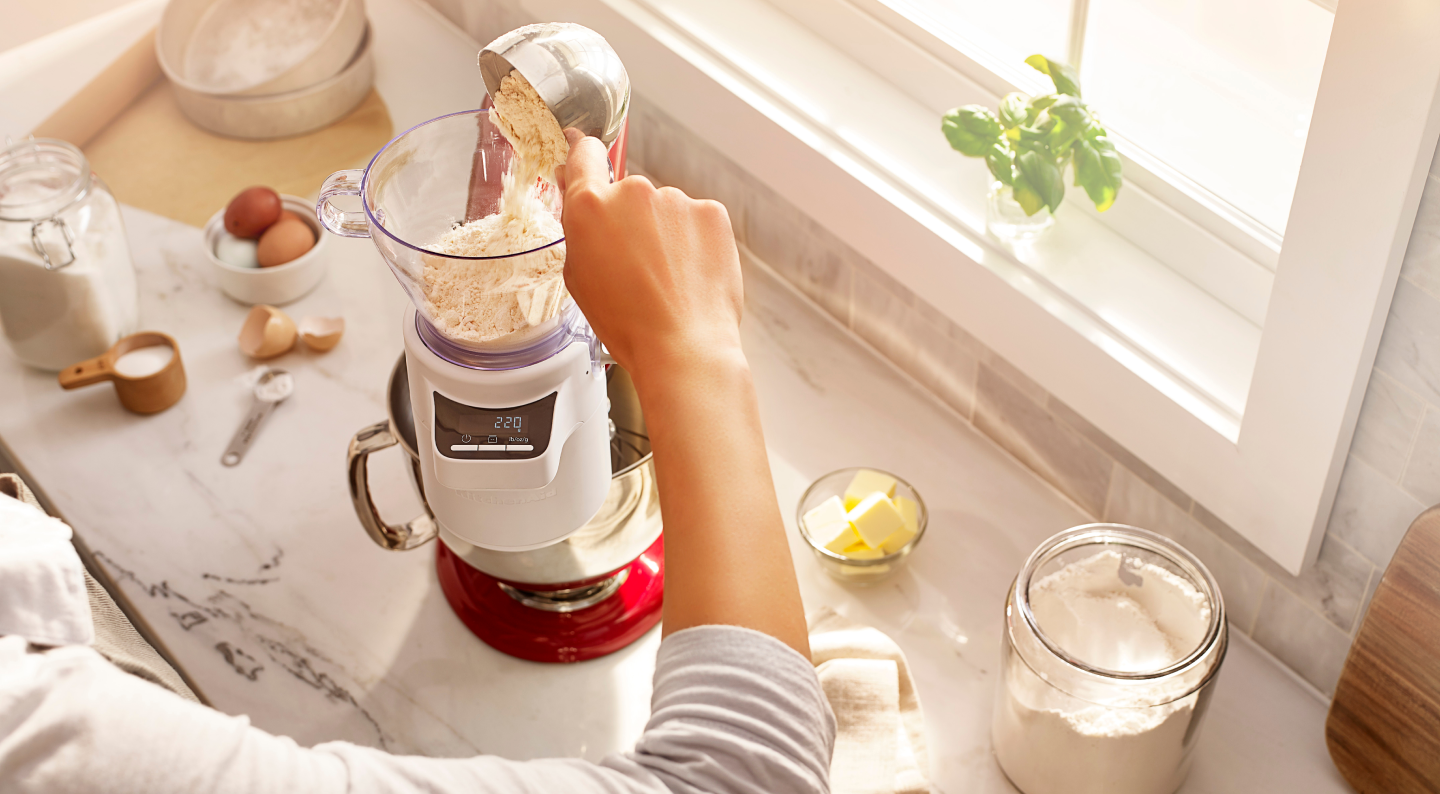 Person adding flour into a KitchenAid® stand mixer