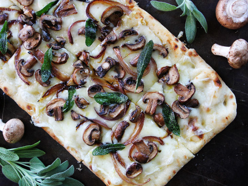 Flatbread pizza topped with cheese, mushrooms and herbs