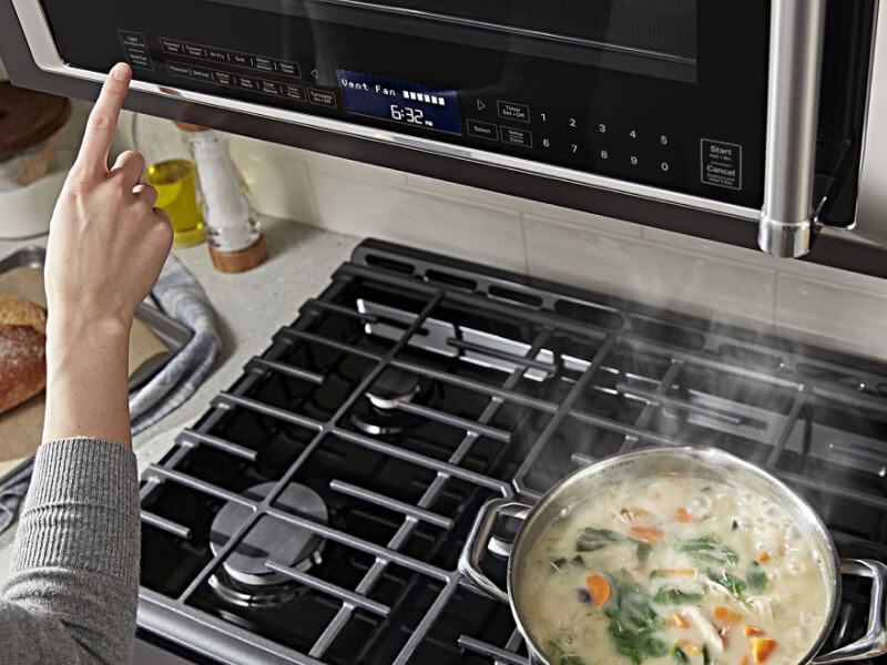 Person selecting a setting on a microwave hood combination