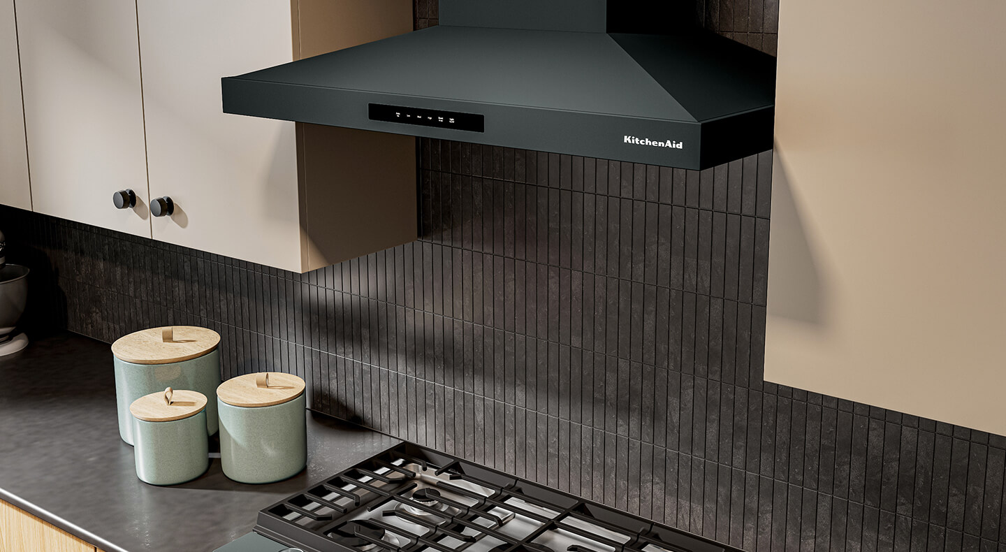 Black KitchenAid® wall-mount range hood above a gas stovetop