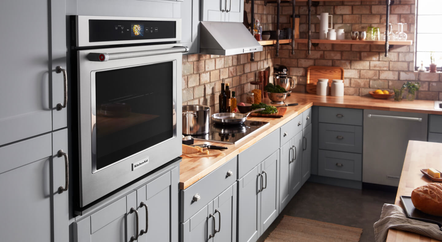 A KitchenAid® wall oven and other appliances in a kitchen with blue cabinets