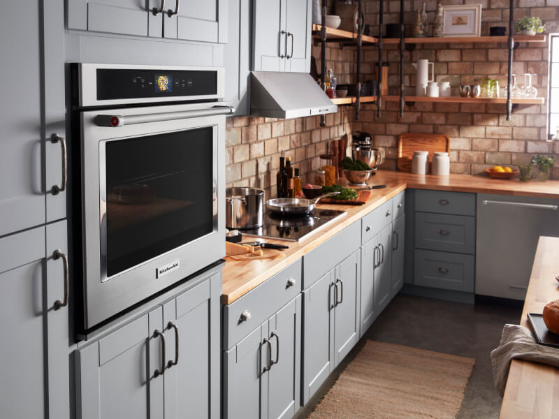 A KitchenAid® wall oven and other appliances in a kitchen with blue cabinets